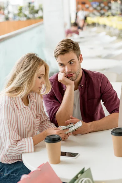 Couple counting cash money at table with coffee cups in cafe — Stock Photo