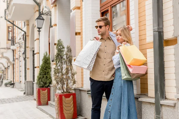 Junges Paar mit Papiertüten posiert auf der Stadtstraße — Stockfoto