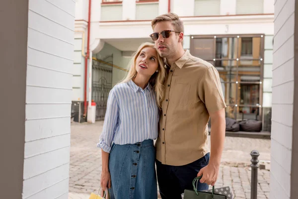 Paar von Einkäufern mit Papiertüten blickt auf Schaufenster in der Innenstadt — Stockfoto