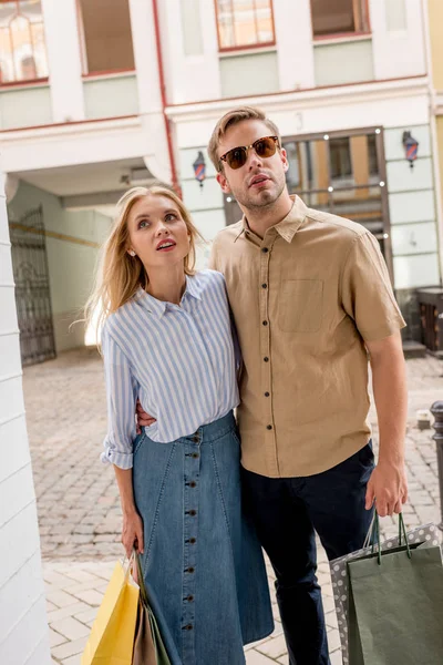 Stilvolles junges Paar mit Einkaufstüten blickt auf Schaufenster in der Stadtstraße — Stockfoto