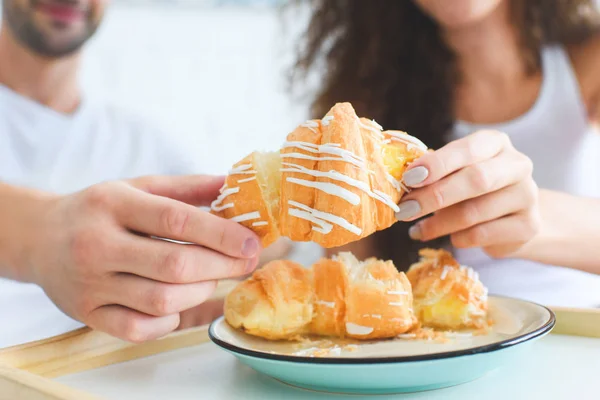 Vista close-up de casal jovem compartilhando croissant para o café da manhã — Fotografia de Stock