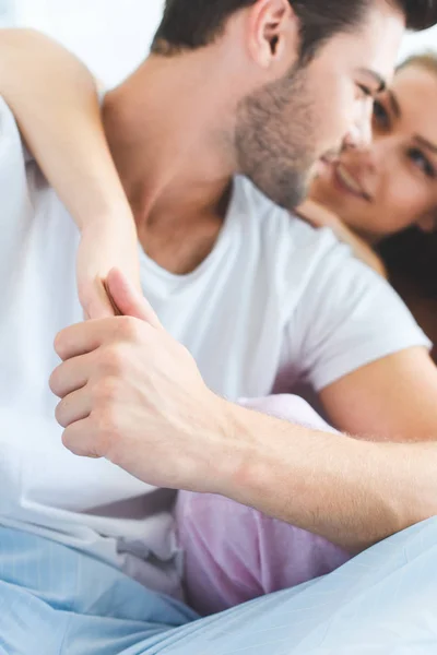 Plan recadré de heureux jeune couple en pyjama étreignant dans la chambre — Stock Photo