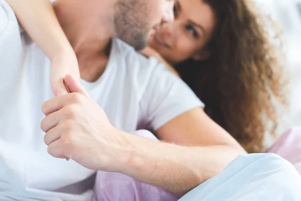 Cropped shot of happy young couple in pajamas hugging on bed — Stock Photo