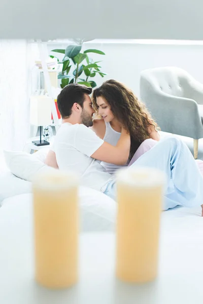 Selective focus of smiling young couple able to kiss on bed — Stock Photo