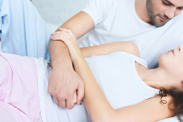 Cropped shot of man in pajamas looking at girlfriend lying on bed — Stock Photo