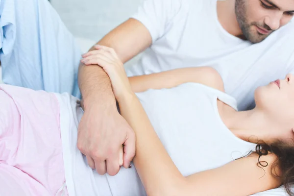 Recortado disparo de hombre en pijama mirando novia acostada en la cama - foto de stock