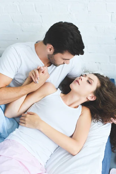 High angle view of young man holding hand of sleeping girlfriend — Stock Photo