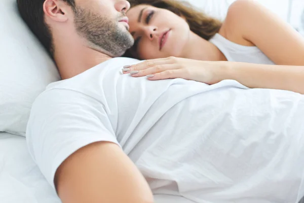Corte tiro de belo jovem casal apaixonado deitado juntos na cama — Fotografia de Stock