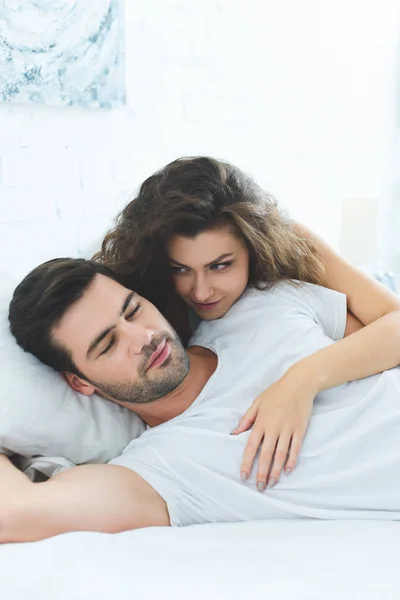 Belle jeune femme heureuse étreignant petit ami dormir sur le lit — Stock Photo