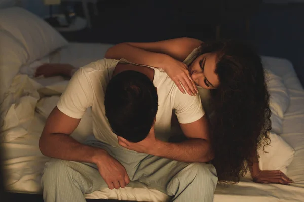 Young woman looking at upset boyfriend sitting on bed at night, relationship difficulties concept — Stock Photo