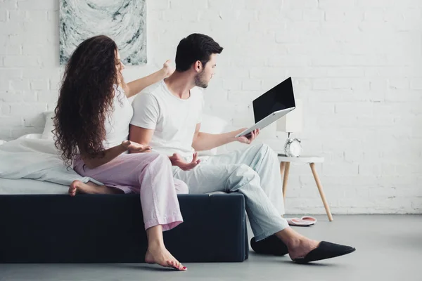 Wütende junge Frau schaut Freund mit Laptop mit leerem Bildschirm an, Konzept für Beziehungsschwierigkeiten — Stockfoto