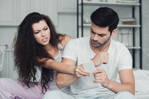 Chateado jovem casal segurando smartphone e brigas, conceito de dificuldades de relacionamento — Fotografia de Stock