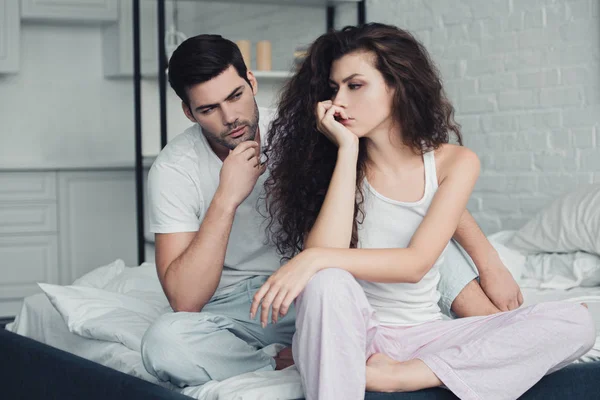 Dissatisfied young couple in pajamas having quarrel on bed — Stock Photo