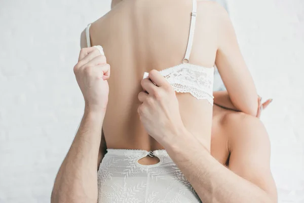 Обрезанный снимок мужчины снимающего лифчик с сексуальной подружки — стоковое фото