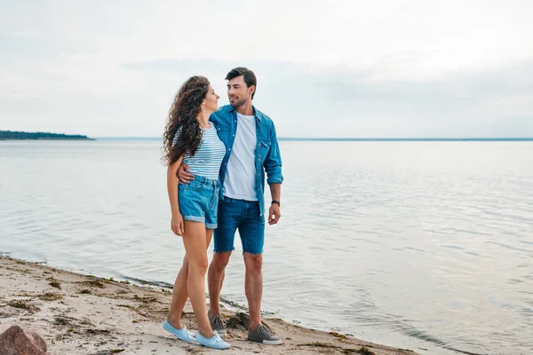 Bonito jovem casal abraçando na praia perto do mar — Fotografia de Stock