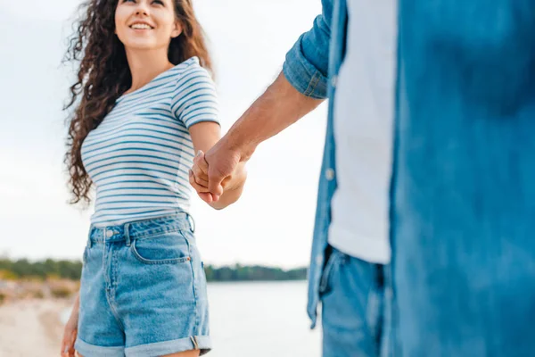 Boyfriend and girlfriend holding hands and walking on beach — Stock Photo