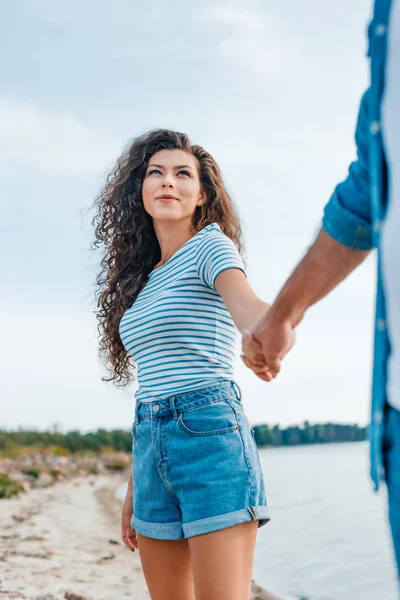 Feliz pareja cogida de la mano y caminando en la playa - foto de stock