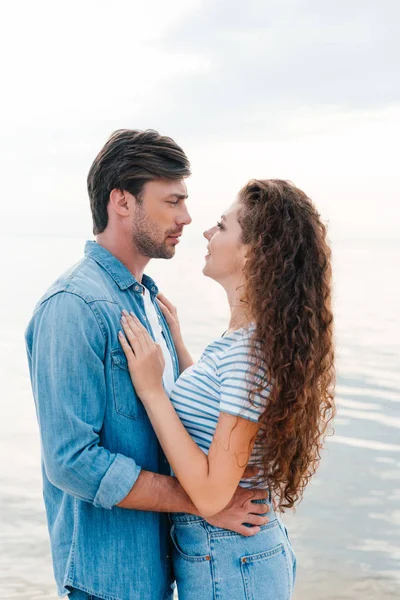 Hermosa joven pareja abrazando cerca del mar - foto de stock