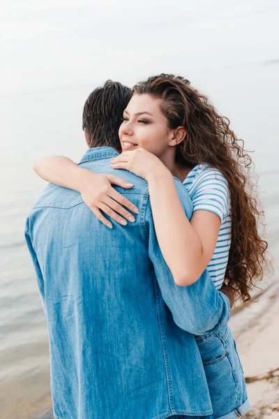 Feliz novia abrazando a su novio cerca del mar - foto de stock