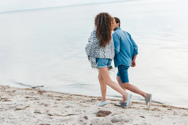 Vue arrière du jeune couple courant sur le bord de la mer — Photo de stock