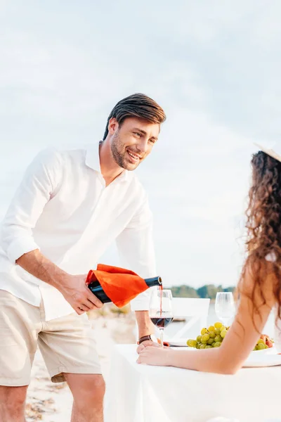 Lächelnder Mann gießt bei romantischem Date im Freien Rotwein ins Glas für Freundin — Stockfoto