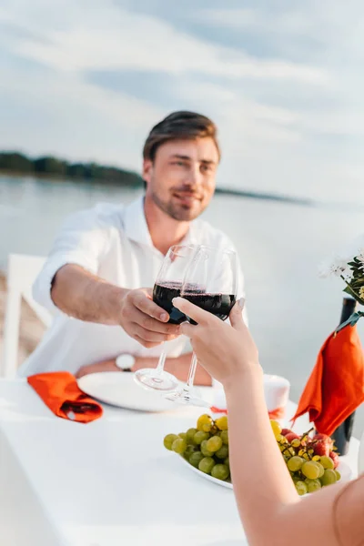 Couple clinking with wineglasses during romantic date on seashore — Stock Photo