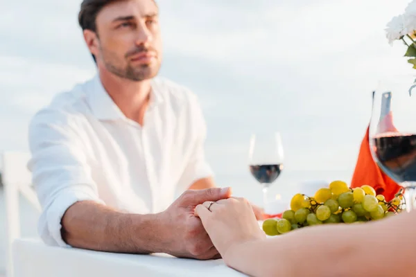 Joven pareja cogida de la mano después de proponer en romántico fecha - foto de stock