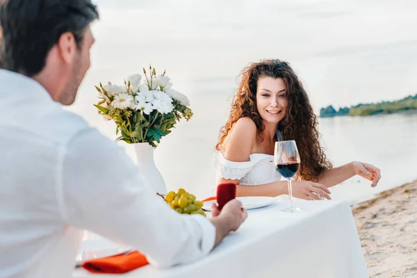 Hombre haciendo proponer con anillo a novia en cita romántica en la orilla del mar - foto de stock