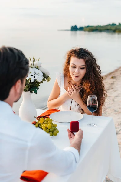 Hombre haciendo proponer con anillo a chica excitada en cita romántica al aire libre - foto de stock