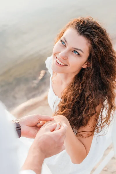 Partial view of man wearing proposal ring on womans finger — Stock Photo