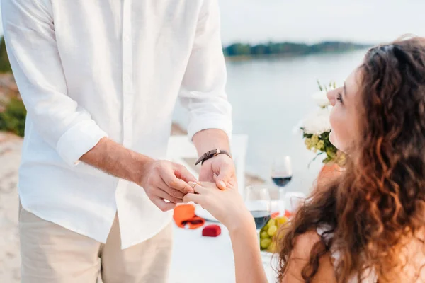 Cropped view of man wearing ring on womans finger after propose on romantic date — Stock Photo