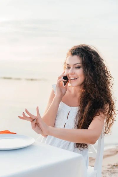 Mujer hermosa emocionada hablando en el teléfono inteligente y mirando en anillo de compromiso en su mano - foto de stock