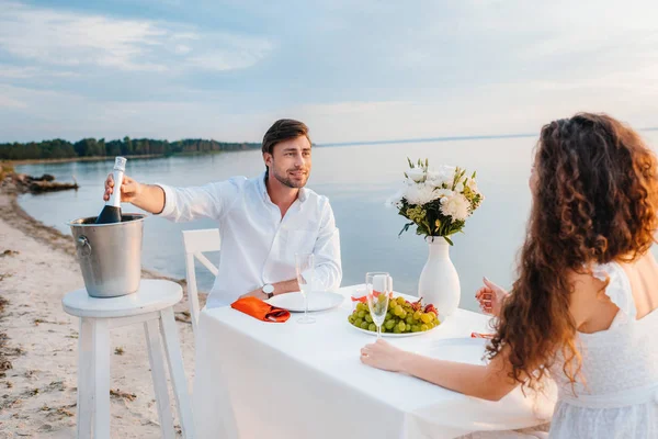 Bell'uomo che prende bottiglia di champagne per appuntamento romantico sulla spiaggia — Foto stock