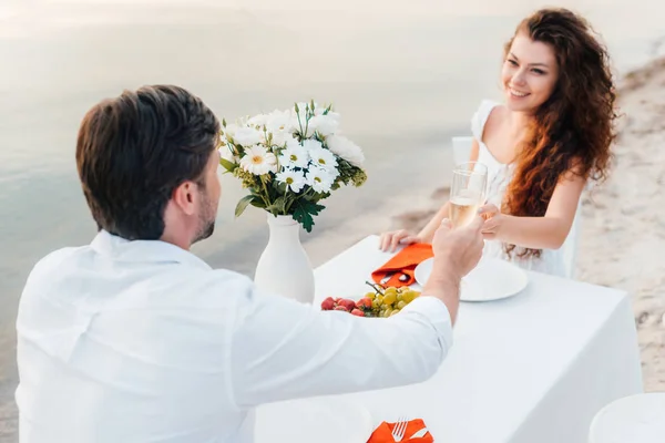Homme et femme griller avec des verres de champagne lors d'un rendez-vous romantique sur la plage — Photo de stock