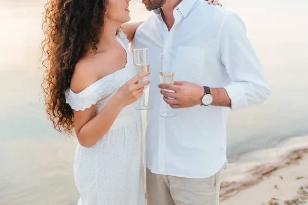 Vista recortada de pareja romántica abrazando y sosteniendo copas de champán - foto de stock