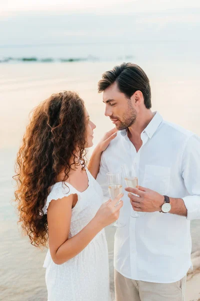 Romantisches Paar, das sich umarmt, Champagnergläser hält und einander ansieht — Stockfoto