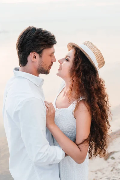Casal feliz olhando um para o outro e abraçando na praia — Fotografia de Stock