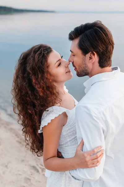 Happy romantic couple looking at each other and embracing on seashore — Stock Photo