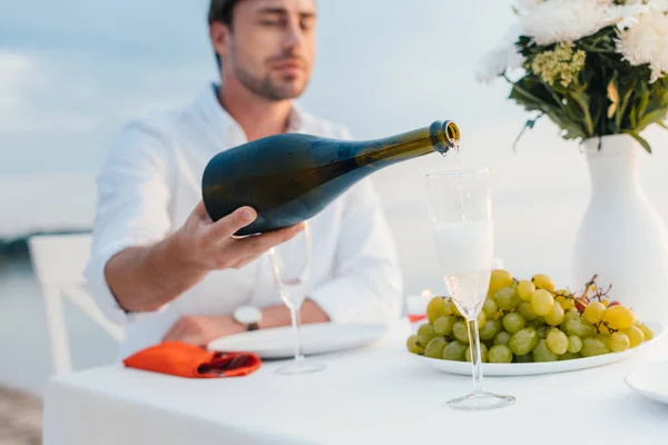 Selective focus of man pouring champagne into glass on romantic date — Stock Photo