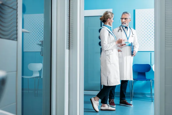 Doctores sonrientes y masculinos hablando en el pasillo del hospital - foto de stock