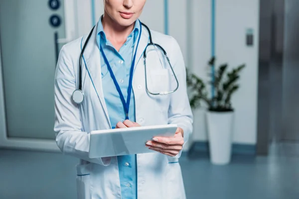 Частковий вигляд жінки-лікаря зі стетоскопом над шиєю за допомогою цифрового планшета в лікарні — стокове фото