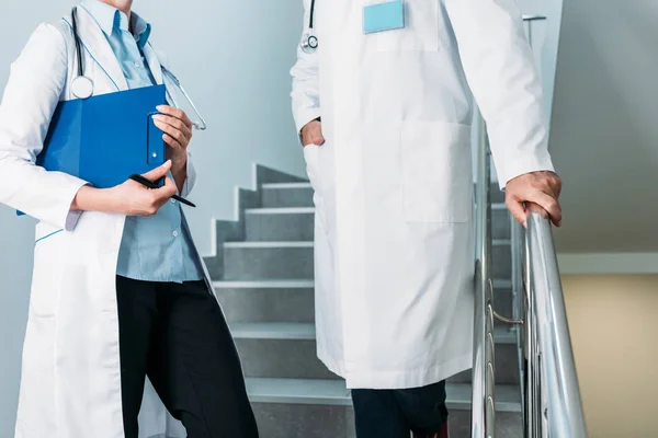 Imagen recortada de médicos hombres y mujeres con estetoscopios de pie en la escalera en el hospital - foto de stock