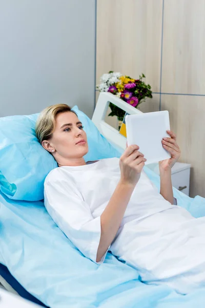 Adulte femme patient utilisant tablette numérique sur le lit dans la chambre d'hôpital — Photo de stock