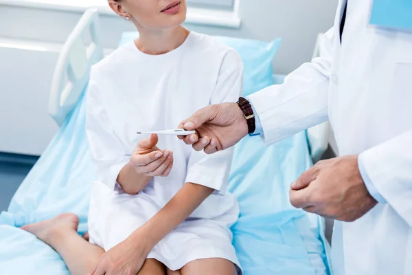 Immagine ritagliata del medico maschio che dà il termometro al paziente femminile nella stanza d'ospedale — Foto stock