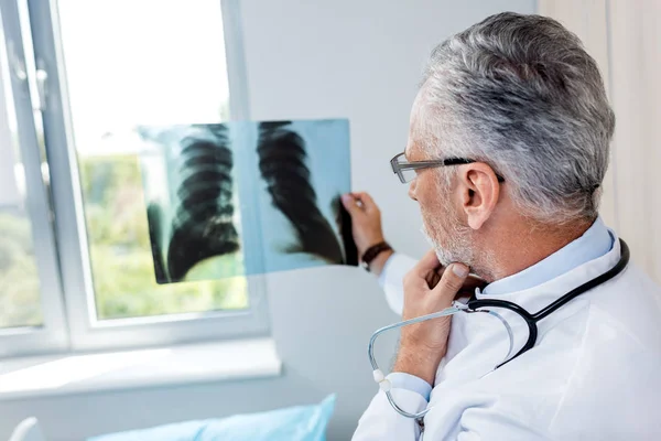 Männlicher Arzt mittleren Alters analysiert Röntgenbild im Krankenhaus — Stockfoto