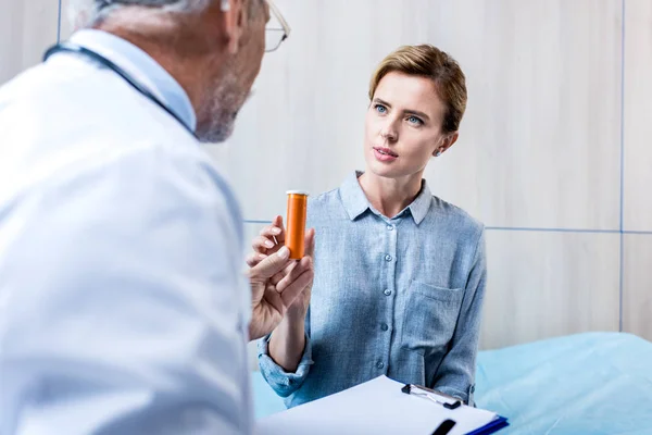 Partial view of male doctor with clipboard giving pills to female patient in hospital room — Stock Photo