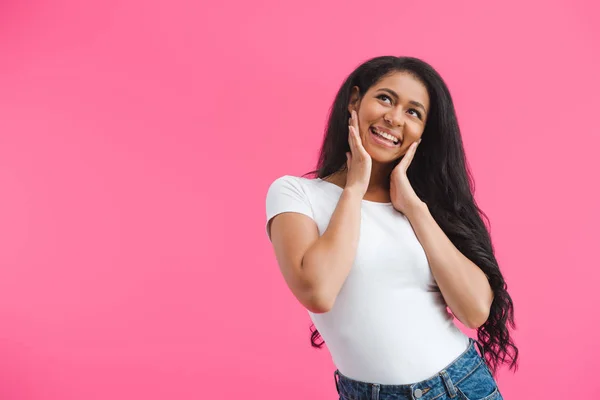 Portrait de femme afro-américaine souriante et rêveuse regardant loin isolé sur rose — Photo de stock