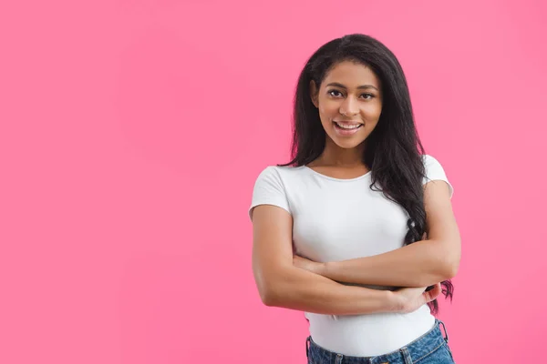 Porträt einer lächelnden Afroamerikanerin mit verschränkten Armen isoliert auf rosa — Stockfoto