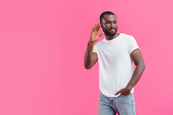 Retrato de hombre afroamericano sonriente saludando a alguien aislado en rosa - foto de stock