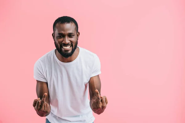 Portrait of cheerful african american man showing middle fingers isolated on pink — Stock Photo
